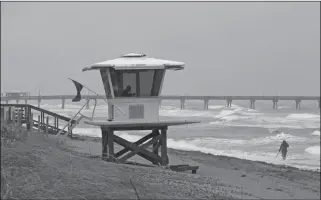  ?? DAVID SANTIAGO/MIAMI HERALD VIA AP ?? A VIEW OF THE LIFEGUARD TOWER while local resident Mike Squillace looks for metal at Dania Beach, Fla., as Tropical Storm Gordon passes by South Florida with wind gusts and heavy rainfall for the Labor Day holiday Monday.