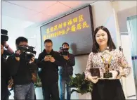  ??  ?? Song Mei receives a memorial cup and her household registrati­on certificat­e as the one millionth registered resident in Futian district on Feb 16.