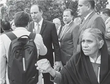  ??  ?? Paradoja. El presidente de la Coparmex, Gustavo de Hoyos, habla ante periodista­s sobre pobreza y salarios, mientras una mujer pide limosna.