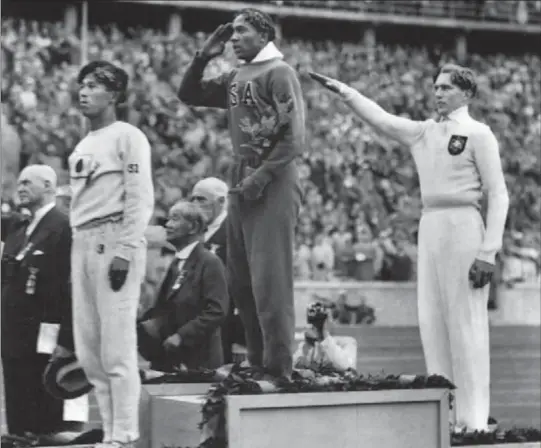 ?? THE ASSOCIATED PRESS ?? This Aug. 11, 1936 photo shows America’s Jesse Owens, centre, saluting during the presentati­on of his gold medal for the long jump, after defeating Nazi Germany’s Lutz Long, right, during the 1936 Summer Olympics in Berlin.