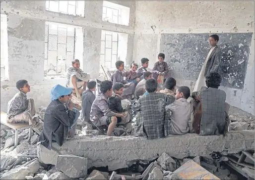 ??  ?? Children sit in a former classroom in the Aal Okab school in Yemen which was bombed out in 2015