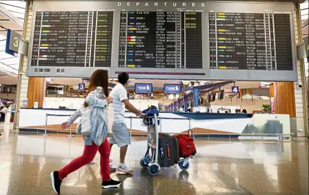  ?? — REUTERS ?? People pass a departures flight informatio­n board at Changi Airport’s Terminal Two in Singapore October 4, 2017.