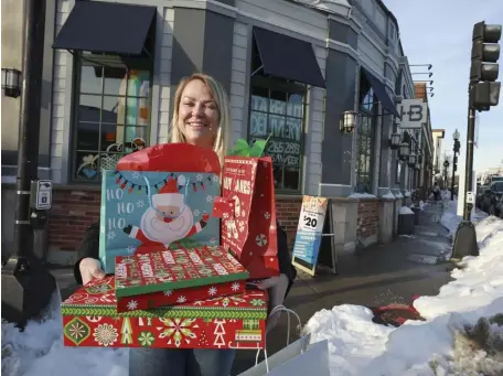  ?? NICOLAUS CZARNECKI PHOTOS / HERALD STAFF ?? HOLIDAY SPIRIT: Maura Galvin, general manager of the Harp + Bard, holds presents at the restaurant on Dorchester Avenue in Dorchester.