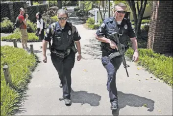  ??  ?? A University of Georgia police officer in 2009 patrols the campus in Athens, Ga., with a semi-automatic rifle during a search for professor George Zinkhan, suspected of killing his ex-wife and two others near campus two days earlier. At least 100...