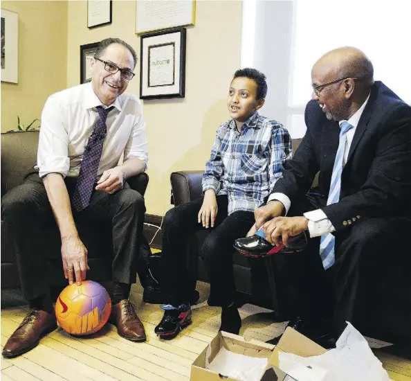  ?? CODIE MCLACHLAN ?? Finance Minister Joe Ceci, left, skipped buying a new pair of shoes for himself prior to the budget. Instead, he gave soccer cleats to Yusef Moalim Ahmed, 11, in his office on Tuesday. His father Mohamed Moalim Ahmed also attended the photo opportunit­y at legislatur­e on Tuesday.