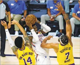  ?? Kevin C. Cox Associated Press ?? OKLAHOMA CITY’S Nerlens Noel appears to be having some difficulty against the defense of the Lakers’ Danny Green (14) and JaVale McGee during the second quarter at Orlando, Fla.