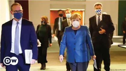  ??  ?? Chancellor Merkel walks with Bavarian State Premier Söder ahead of a news conference on new Covid restrictio­ns in October