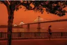  ?? Photograph: San Francisco Chronicle/Hearst Newspapers/Getty Images ?? A woman jogs by the Bay Bridge as dark orange skies caused by wildfire smoke hang over downtown San Francisco, California.