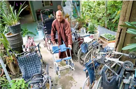  ?? Photo plo.vn ?? Monk Đức Minh stands in the middle of several old wheelchair­s he has collected and repaired for people with disabiliti­es.