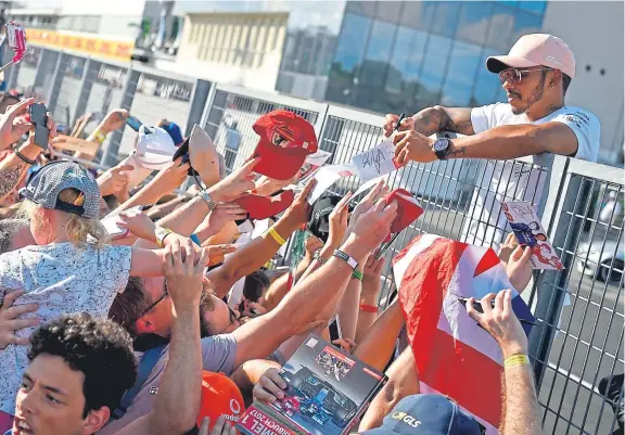  ?? Picture: AP. ?? Lewis Hamilton signs autographs for fans on the Hungarorin­g circuit in Mogyorod as he prepares for the Hungarian GP.