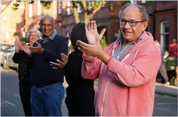  ??  ?? SHOWING WE CARE: Neighbours gather in the street during Thursday’s Clap for Carers ritual