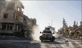  ?? ASMAA WAGUIH / AP ?? An armored vehicle drives through Raqqa, Syria, on Wednesday. The Kurdish-led Syrian Democratic Forces said that their troops have taken full control of the city. The U.S.-led coalition cautioned that some 100 militants may still be hiding in the city.