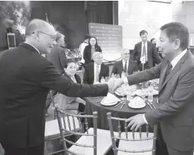  ?? ?? RCBC chairman Helen Dee (middle seated) watches as Diokno and Tetangco shake hands.
