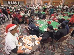  ??  ?? DeLon Price and her daughter Erin spend their third Christmas volunteeri­ng at the 28th annual Christmas Family Feast on Sunday at the Wisconsin Center in Milwaukee.