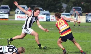  ??  ?? Longwarry’s Riley Rundell searches for a way past his Poowong opponent; Photograph­s: Longwarry Football/Netball Club.