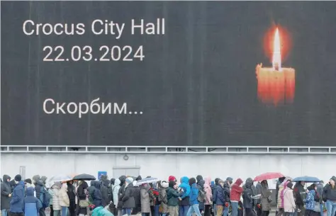  ?? — Reuters file photo ?? People line up to lay flowers at a makeshift memorial to the victims of a shooting attack set up outside the Crocus City Hall.