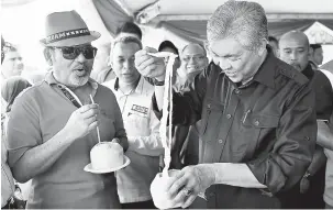  ?? — Gambar Bernama ?? BEGINI CARANYA: Ahmad Zahid (kanan) menunjukka­n kemahirann­ya mengeluark­an isi kelapa ketika melawat tapak pameran selepas merasmikan Karnival Jalinan Peladang Peringkat Negeri Perak di Parlimen Bagan Datuk semalam.