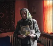  ?? RODRIGO ABD/ASSOCIATED PRESS ?? Nadiya Trubchanin­ova, 70, stands in her bedroom holding a portrait of her sons Oleg Trubchanin­ov, 46, and Vadym, 48, who was killed by Russian soldiers last March 30in Bucha, in the outskirts of Kyiv, Ukraine, Thursday, April 14, 2022.