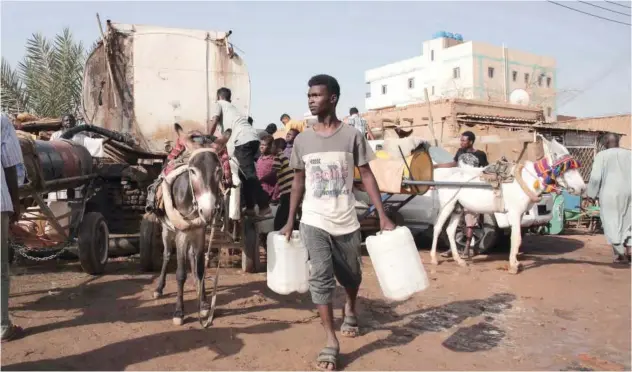  ?? Associated Press ?? ↑
People gather to collect water in Khartoum on Sunday.