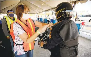  ?? Al Seib Los Angeles Times ?? ROWEL SALVADOR, assistant principal at L.A.’s John Muir Middle School, rode his motorcycle to SoFi Stadium on Monday to get a shot at the nation’s largest vaccinatio­n site specifical­ly for education workers.