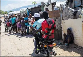  ?? (File Photo/AP/Rodrigo Abd) ?? G9 coalition gang members ride a motorcycle Oct. 6 through the Wharf Jeremy street market in Port-au-Prince, Haiti.