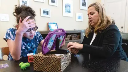  ?? ANTHONY VAZQUEZ/SUN-TIMES ?? Celeste O’Connor and her daughter Chloe Eugenio try to find certain word on a device that lets her speak at their Chicago home on Aug. 5.