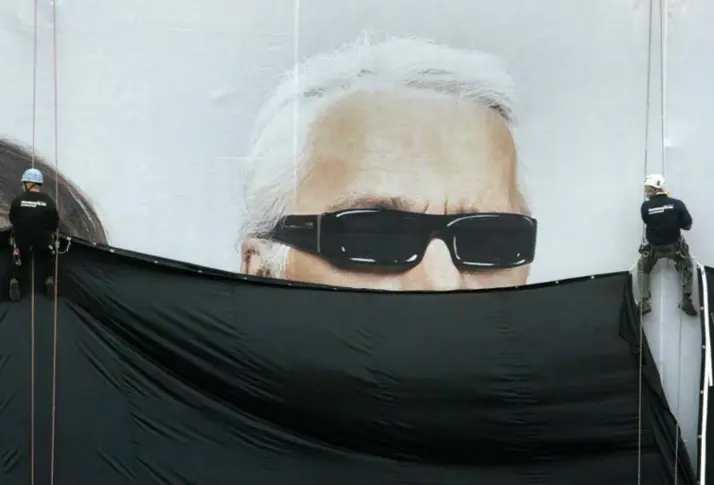  ?? © reuters ?? Werkmannen onthullen een 1.500 m² groot reclamebor­d voor de samenwerki­ng tussen Karl Lagerfeld en H&amp;M in 2004..