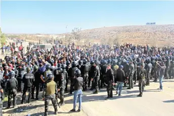  ?? — AFP photo ?? Members of the security forces face Tunisian anti-government demonstrat­ors during a general strike, following the reopening of a rubbish dump, in the Tunisian town of Aguereb in the central region of Sfax.