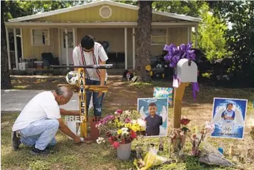  ?? JAE C. HONG ASSOCIATED PRESS PHOTOS ?? Jose Mata (top), a brother of Xavier Lopez, and an unidentifi­ed man place a wooden cross at a memorial honoring Xavier outside his home in Uvalde, Texas. Xavier was among those killed in last week’s shooting.