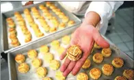  ?? PHOTOS BY ANTHONY WALLACE / AFP ?? Chef Yip Wing-wah
uses dough to wrap the filling of his signature “Spring-Moon mini egg-custard mooncakes” at Hong Kong’s Peninsula Hotel.