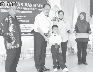  ??  ?? NASRUN menyampaik­an bantuan awal persekolah­an RM100 kepada murid SK Kunak 2 sambil diiringi Aminah (dua kanan).