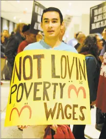  ?? Lori Van Buren / Albany Times Union ?? Daniel Fitzsimmon­s, of Bethlehem, N.Y., holds a sign as fast food workers and other rally in support of a $15 per hour minimum wage at the Empire State Plaza in 2015 in Albany, N.Y.