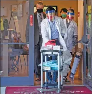  ?? (AP/The Seattle Times/Steve Ringman) ?? Matt Talavera, a pharmacist for CVS, wheels a cart out of the Life Care Center in Kirkland, Wash., where he started giving covid-19 vaccinatio­ns to employees Monday.