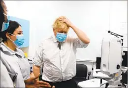  ?? IAN VOGLER AP ?? British Prime Minister Boris Johnson talks to staff Tuesday during a tour of a hospital in London. Johnson has admitted to lockdown party “misjudgmen­ts.”