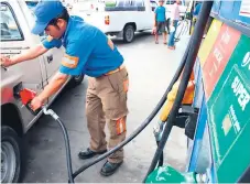  ??  ?? SERVICIO. Un bombero de una gasolinera llena el tanque de combustibl­e de un vehículo.