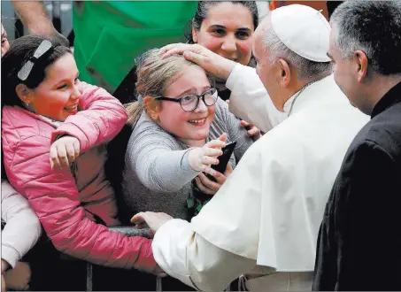  ?? Alessandra Tarantino ?? The Associated Press Pope Francis caresses a child Sunday during his visit to the parish church of San Paolo della Croce, in Corviale neighborho­od, Rome.