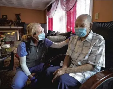  ?? Steven Senne Associated Press ?? GERIATRICI­AN Megan Young, left, offers support to Edouard Joseph, 91, moments after giving him a COVID-19 vaccinatio­n this month at his home in the Mattapan neighborho­od of Boston.