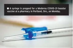  ?? The Associated Press ?? ■ A syringe is prepped for a Moderna COVID-19 booster vaccine at a pharmacy in Portland, Ore., on Monday.