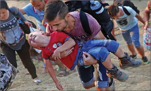  ??  ?? Desperatio­n: A young Syrian boy cries as his father carries him uphill to a crossing on the Greek border with Macedonia yesterday