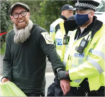  ??  ?? Led away: One of the Extinction Rebellion mob at Broxbourne who had chained themselves to bamboo frames to block the print works exit