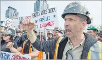  ?? CP PHOTO/PAUL CHIASSON ?? Striking constructi­on workers walk the picket line in front of a constructi­on site Wednesday in Montreal. A union alliance representi­ng about 175,000 Quebec constructi­on workers has launched an unlimited general strike.