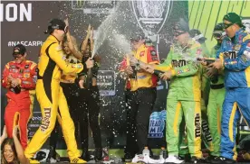  ?? AP Photo/David Graham ?? ■ Kyle Busch, front left, celebrates with teammates in Victory Lane after winning the NASCAR Cup Series season championsh­ip Sunday in Homestead, Fla.