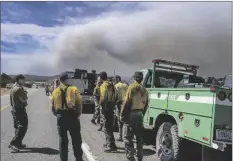  ?? ROBERTO E. ROSALES/AP ?? Wildland firefighte­rs from several agencies throughout the country wait along state road 283 to be sent into the Hermits Peak and Calf Canyon Fires burning just west of Las Vegas, N.M.