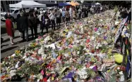  ?? AP PHOTO BY MARK BAKER ?? People view messages at a floral tribute at the Botanical Gardens in Christchur­ch, New Zealand, Tuesday, March 19. Christchur­ch was beginning to return to a semblance of normalcy Tuesday. Streets near the hospital that had been closed for four days reopened to traffic as relatives and friends of Friday’s shooting victims continued to stream in from around the world.