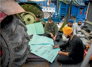  ?? AP ?? Young farmers make placards as they block a major highway during a protest at the DelhiHarya­na state border against India’s new farming laws, which they say will result in them being exploited by big corporatio­ns.