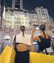  ?? EVAN AGOSTINI/INVISION ?? Models stop to watch themselves June 28 in the Marc Jacobs fall/winter 2021 fashion show projected on the exterior of Bergdorf Goodman department store in New York.