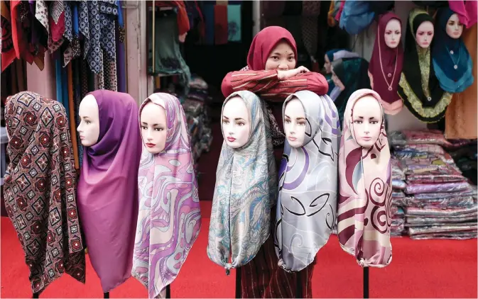  ??  ?? KUALA LUMPUR: An employee waits for customers at a hijab shop in Kuala Lumpur yesterday. — AFP