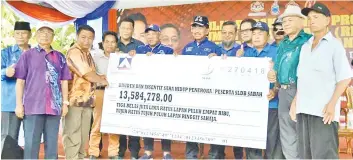  ??  ?? Musa presenting the dividend and incentives for SLDB settlers and participan­ts in Sabah yesterday.