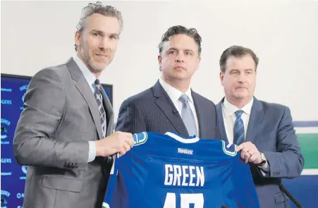  ?? JONATHAN HAYWARD, THE CANADIAN PRESS ?? Canucks president Trevor Linden, left, and general manager Jim Benning, right, introduce the Canucks new head coach Travis Green on Wednesday. Green spent the past four seasons coaching the Canucks’ AHL affiliate in Utica, New York.