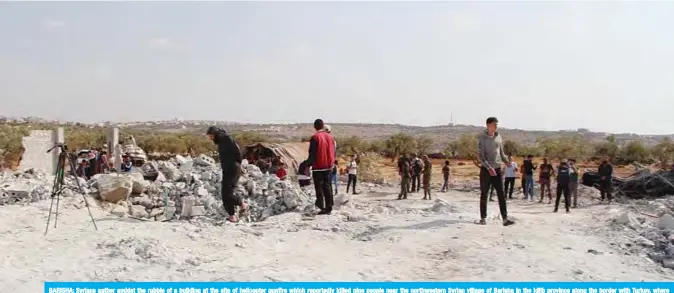  ?? —AFP ?? BARISHA: Syrians gather amidst the rubble of a building at the site of helicopter gunfire which reportedly killed nine people near the northweste­rn Syrian village of Barisha in the Idlib province along the border with Turkey, where “groups linked to the Islamic State (IS) group” were present, according to a Britain-based war monitor with sources inside Syria.